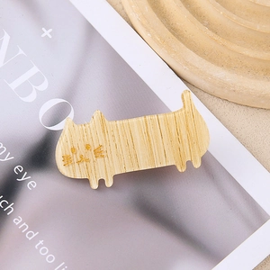 Cute wood-textured cat hair clip with minimalist silhouette on a beige tray