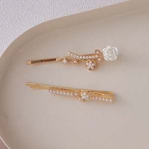 Detailed close-up of French vintage gold hair clips with white roses and pearls