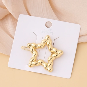 Detail view of a gold star-shaped hair clip with twisted rope texture on a display card