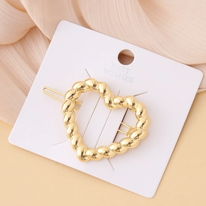 Detail of twisted gold heart hair clip on a white card with Best Wishes text