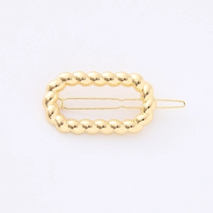 Detail of a golden rectangular hair clip with a polished twisted rope texture