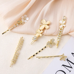 Dettaglio di un set di 6 fermagli dorati con perle, strass e piccoli fiori bianchi