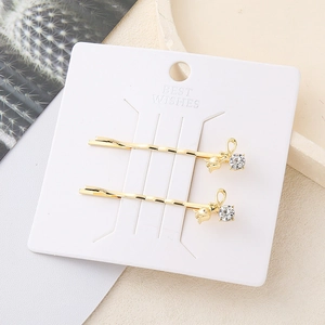 Juego de pinzas para el cabello doradas con flores y pedrería en tarjeta de regalo