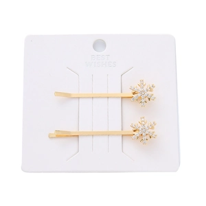 Horquillas de copo de nieve doradas con perlas y strass en una tarjeta blanca
