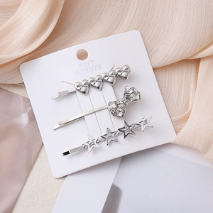 Three-piece set of silver heart, bow, and star hair clips with rhinestones on a card