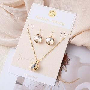Detail van elegante gouden sieradenset met champagne kristallen op een witte kaart