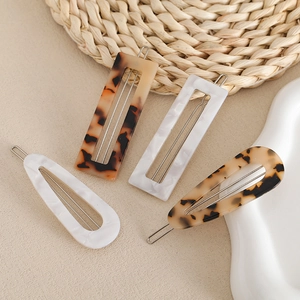 Set of four French acetate hair clips in tortoiseshell and marble on a white ceramic plate