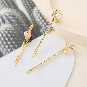 Detalle de set de pinzas para el cabello doradas con tulipán rosa y adornos de perlas