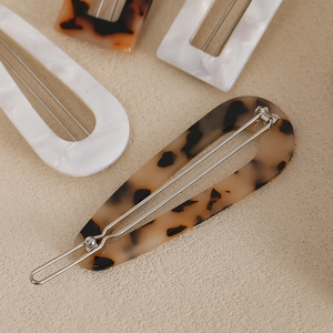French retro oval acrylic hair clips in tortoiseshell and marble patterns on sand texture
