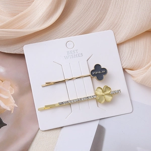 Detail of two-piece clover hair clips with POPULAR text and rhinestones on card