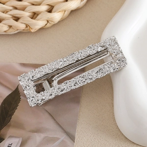 Detail of silver textured rectangular hair clip with hollow design and spring duckbill clamp