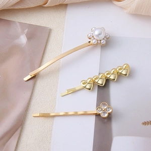 Detailed view of 3-piece gold hair clip set with pearls, hearts and clover charms