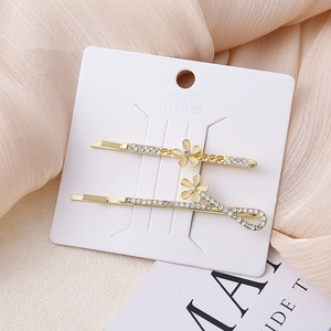 Detail van twee goudkleurige haarclips met witte strassteentjes en gele bloemmotieven