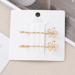 Lot de deux barrettes à fleurs dorées évidées avec strass brillants sur carte blanche