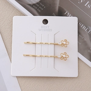 Détail de barrettes à fleurs dorées ornées de perles et de strass brillants sur support