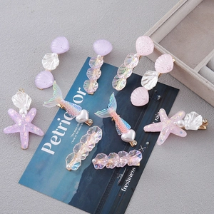 Macro detail of mermaid tail and starfish hair clips with glitter finish and faux pearls