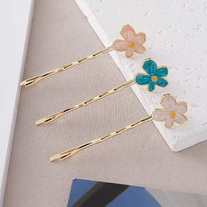 Détails de trois barrettes à fleurs colorées en émail avec base métallique ondulée dorée