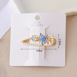 Ocean themed gold hairpin with blue starfish, white pearls and shell on display card