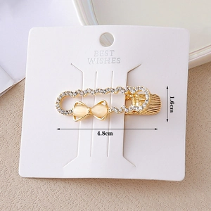 Golden safety pin hair clip with rhinestone bow and teardrop cat eye stones