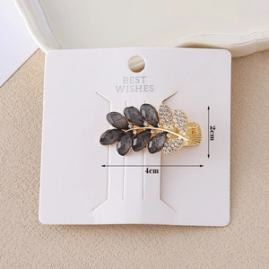 Leaf-shaped golden hair clip with dark grey gemstones and sparkling rhinestones