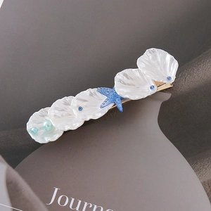 Detail view of a shell starfish hair clip with blue rhinestones and pearls on gold metal