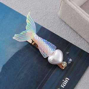 Macro detail of mermaid tail hair clip with white heart pearl and crystal on gold alloy base