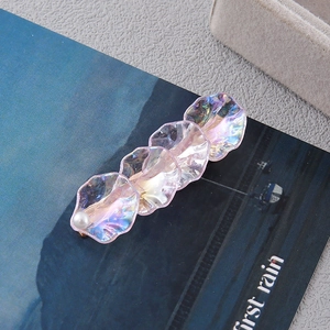 Close-up of iridescent pink flower hair clip with pearl accent on a sea-themed magazine