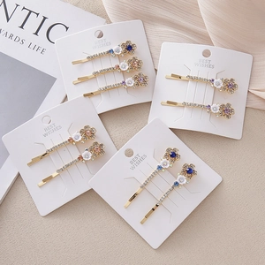 Set de barrettes à fleurs blanches et strass colorés sur monture en métal doré