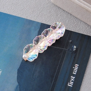 Detail of iridescent acrylic petal hair clip with white pearl on a deep blue background