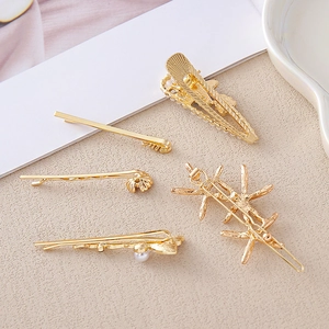 Détail d'un ensemble de 5 barrettes dorées avec perles de culture et motifs étoiles
