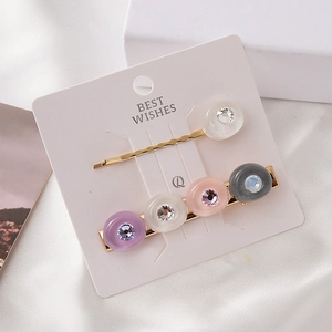 Barrettes élégantes en alliage doré avec résine et strass sur carte blanche