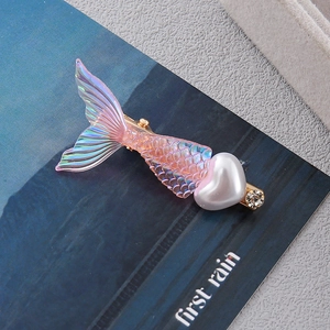 Detailed macro of a fishtail hair clip with iridescent pink scales and pearl heart decoration