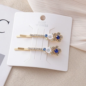 Vue détaillée de barrettes à fleurs avec strass bleus et finition en métal doré