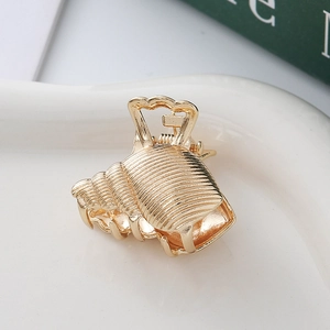 Elegant gold seashell hair claw clip with spiral texture on a white ceramic tray