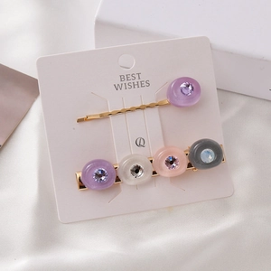 Set de barrettes dorées élégantes avec strass colorés sur une carte de support