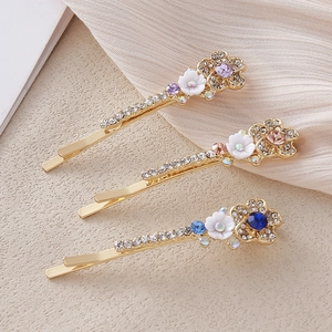 Détail de trois barrettes à fleurs avec cristaux colorés et base en alliage doré