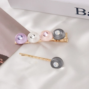 Détail des barrettes à cheveux macarons avec strass sur fond de soie blanche élégant