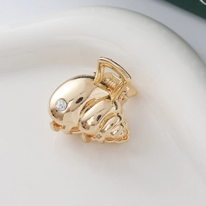 Detail of golden seashell mini hair claw clip with crystal rhinestone and metallic finish