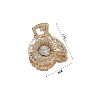 Detail view of a 2.3x2cm golden shell hair clip featuring a central crystal rhinestone