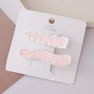 Lot de deux barrettes à cheveux roses à pois au design ondulé sur carte blanche
