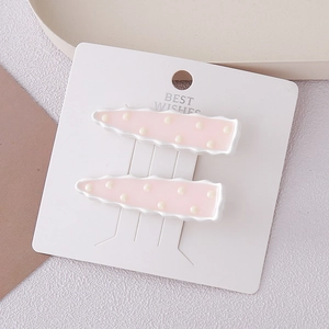 Gros plan de barrettes à pois roses avec bords ondulés sur une carte de présentation
