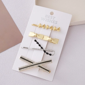Silver bow hair clips set with rhinestones and black beads on a white card