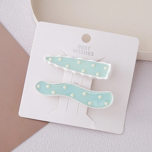 Gros plan de barrettes à pois bleu clair aux motifs ondulés et zigzag sur une carte