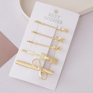 Detailed set of five matte gold bow hair clips with faux pearls on display card