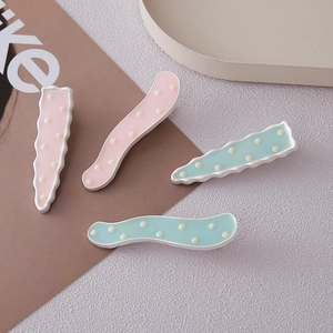 Détail de barrettes à cheveux ondulées rose et vert menthe avec motifs à pois