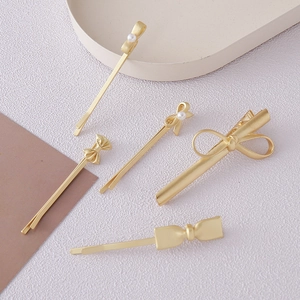 Detailed macro view of 5-piece matte gold bow hair clips set with imitation pearls