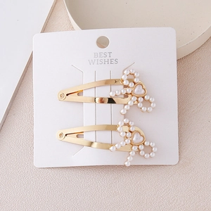 Golden alloy teardrop hair clips with pearl bow and heart bead on white card
