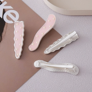 Vue détaillée des barrettes à pois roses avec motifs ondulés et pince crocodile en métal