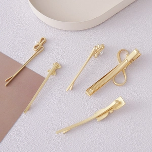 Detailed set of golden bow hair clips with faux pearls and twisted metal designs
