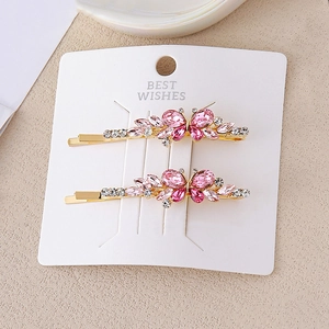 Barrettes à cheveux papillon en cristal rose et or présentées sur une carte